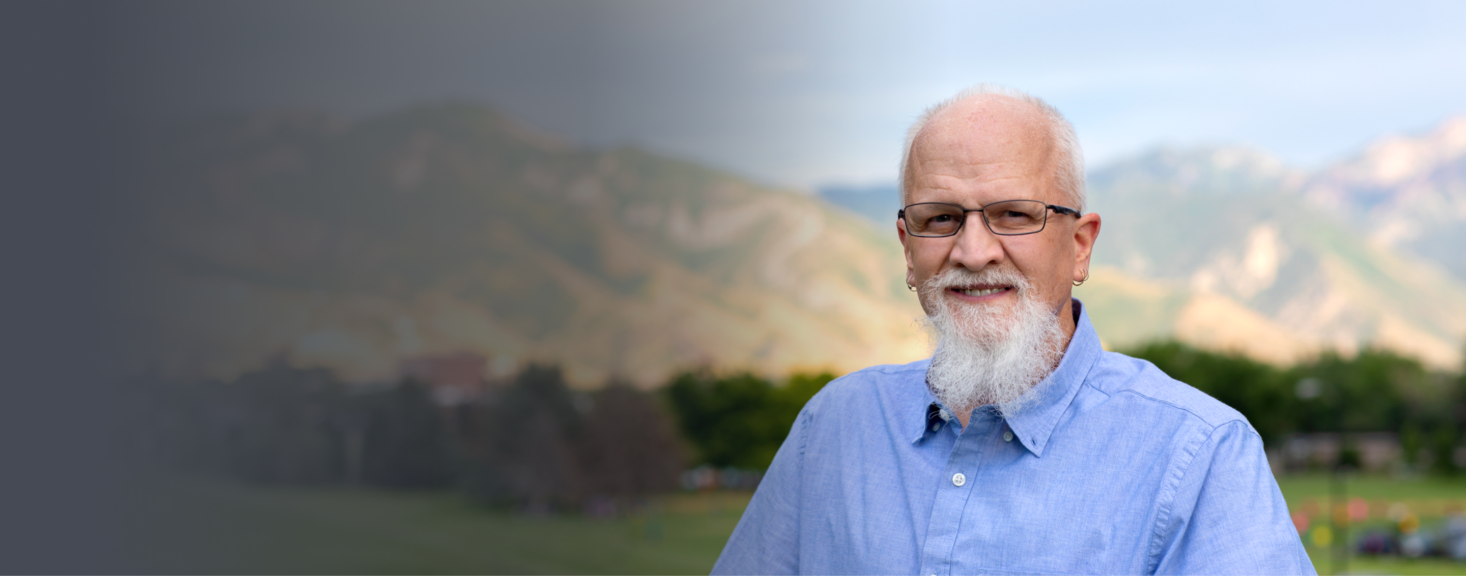 Dan, male patient with PBA in his 60s, standing in front of a mountainous landscape