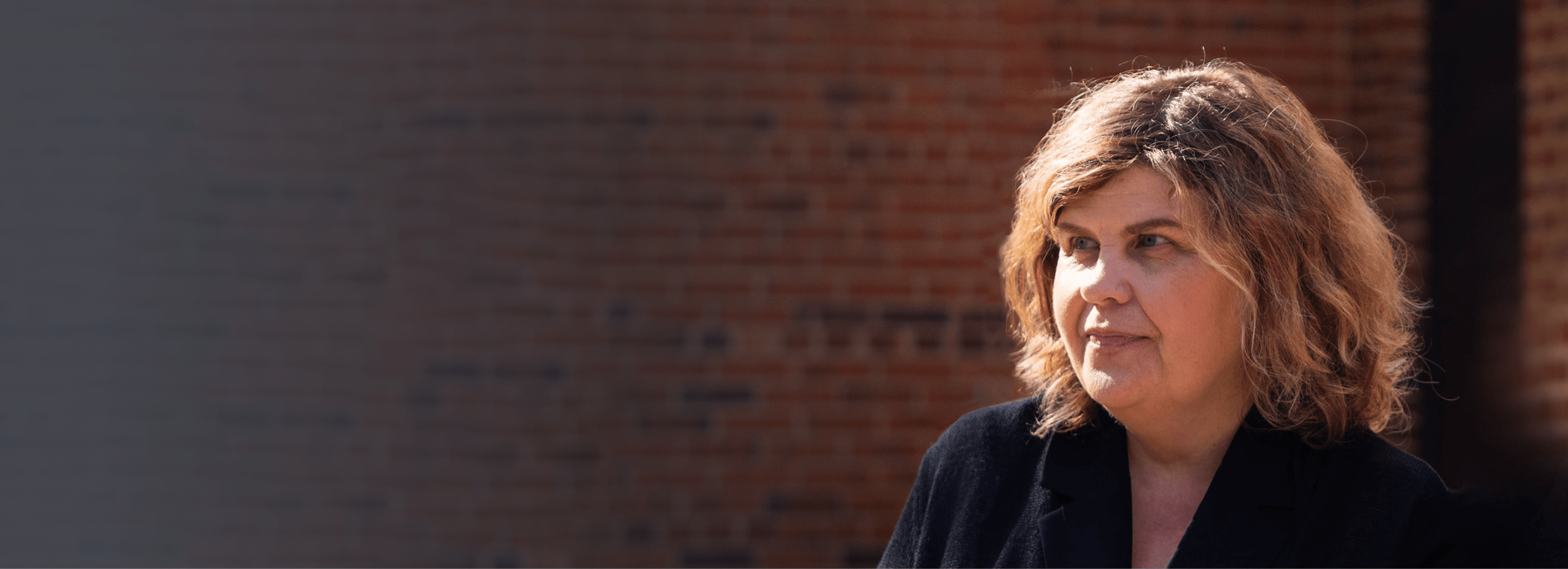 Carol, female patient with PBA in his 60s, standing in front of a mountainous landscape